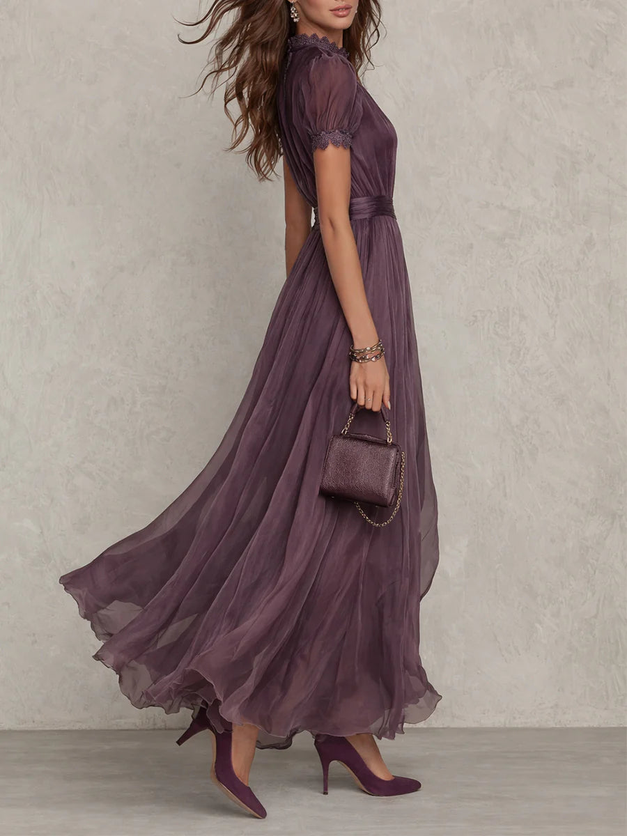 Woman posing in an elegant purple evening dress on a plain background.