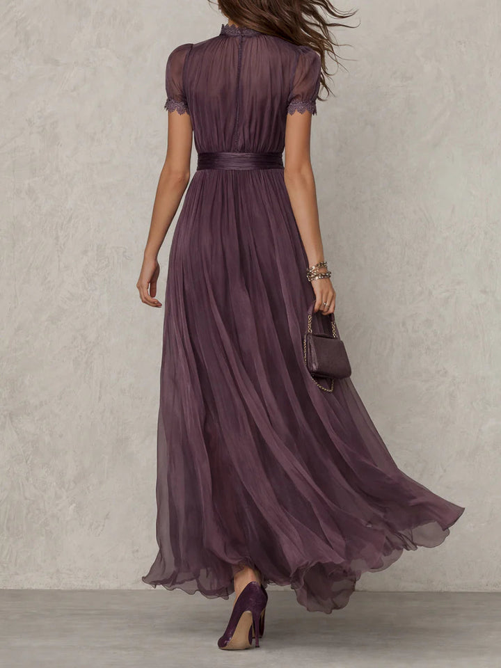 Long sleeve purple formal dress displayed on a female model with plain backdrop, back view