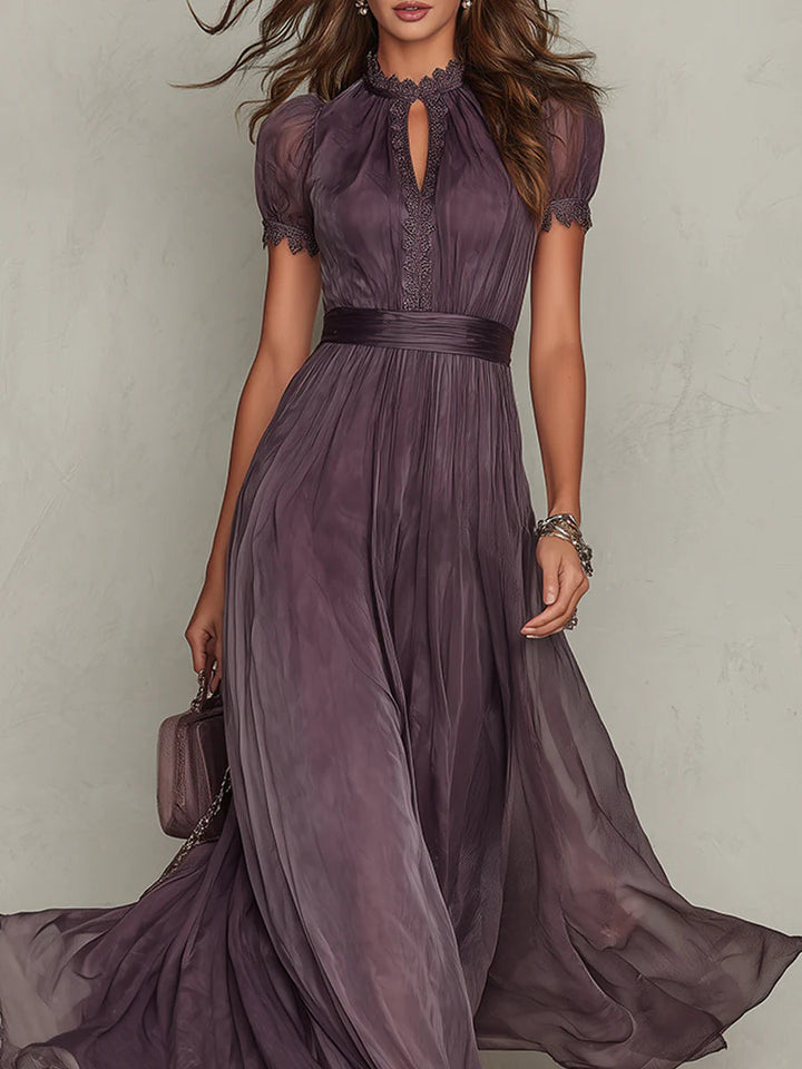 Woman standing in a flowing purple dress for formal occasions on a plain background.