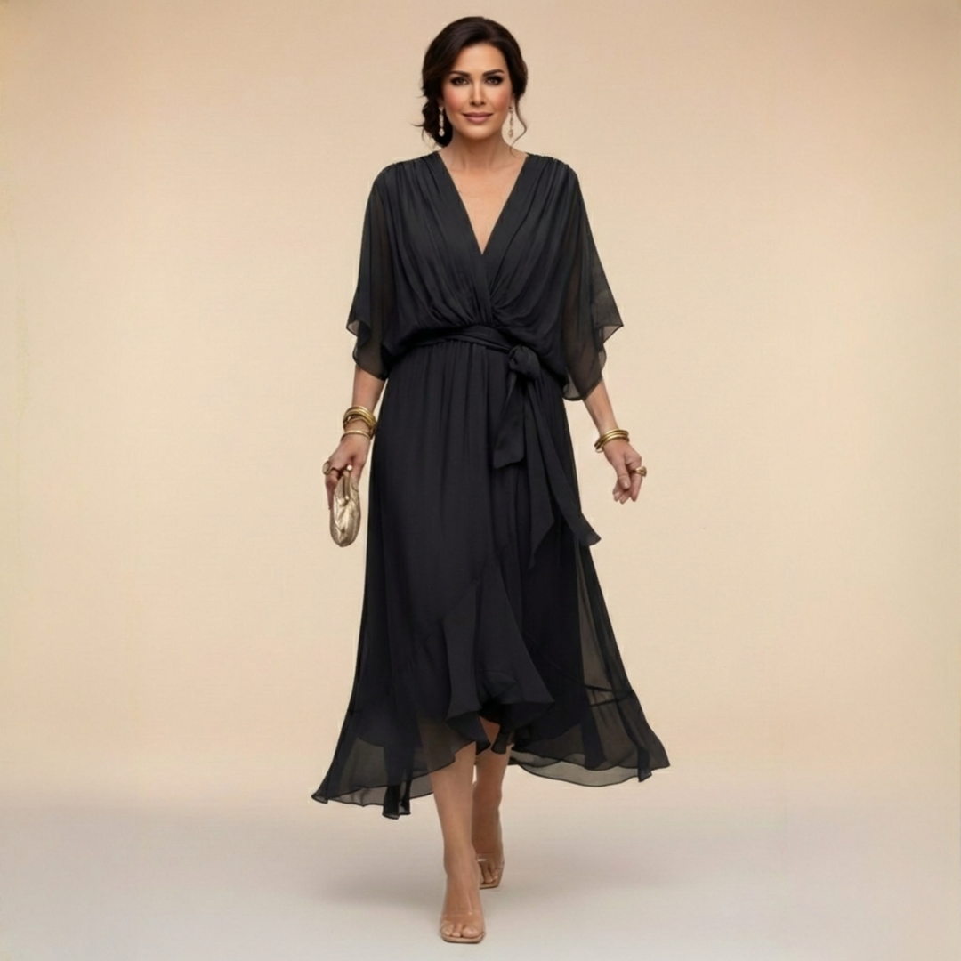Female in a wrap midi dress with 3/4 sleeves on a plain background.
