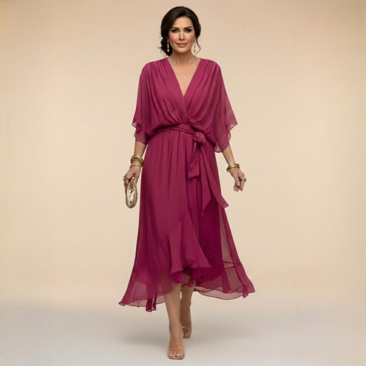 Woman in a 3/4 sleeve wrap midi dress on a plain background.