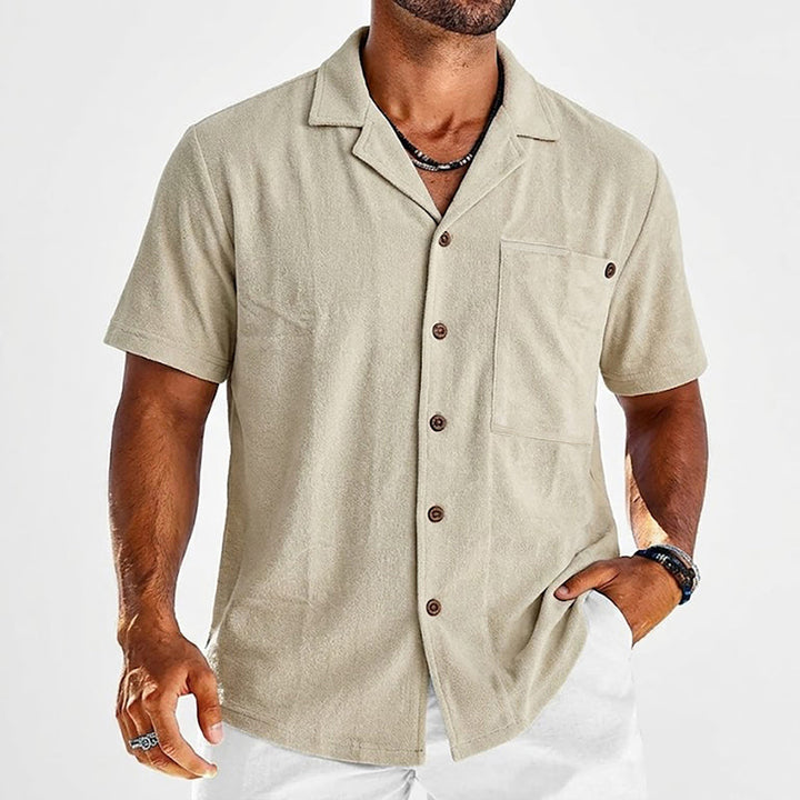 Male model wearing a relaxed open collar shirt against a plain background.