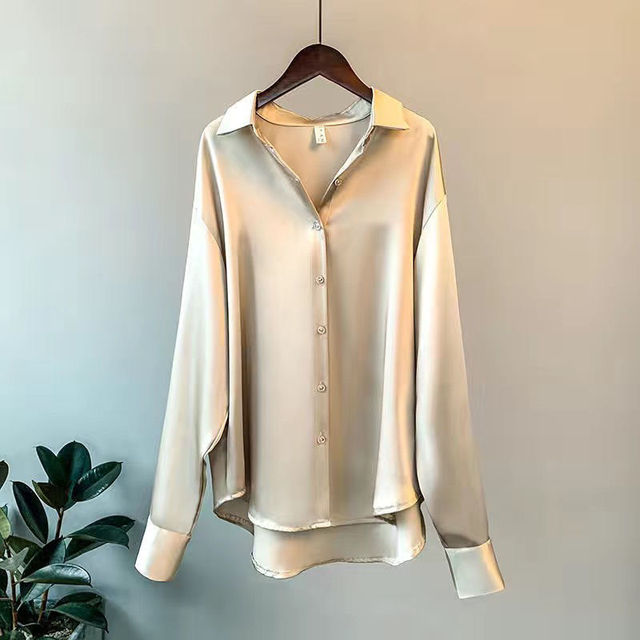 Female wearing a refined office blouse with a polished look on a clean background.