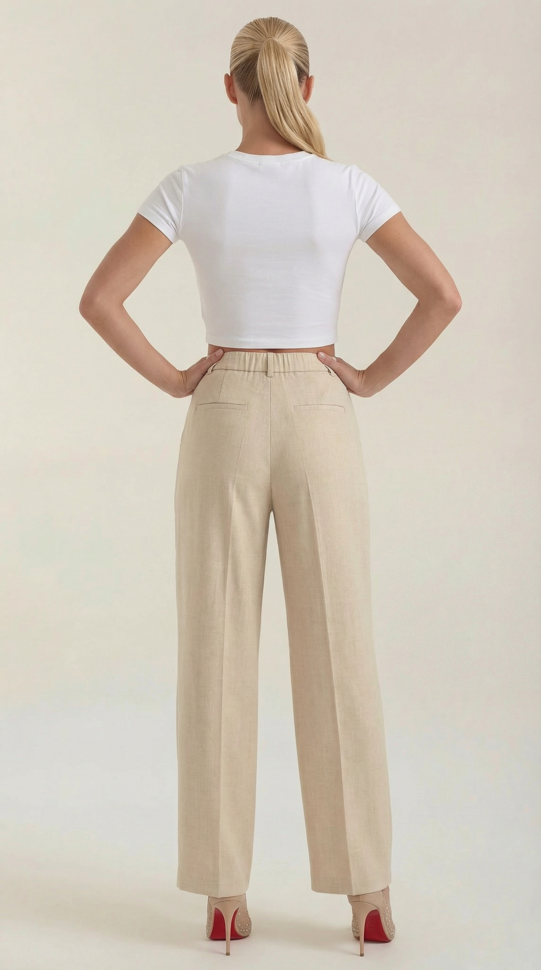 Woman wearing tailored trousers back angle on plain background.