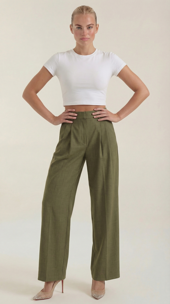 Female model posing casually in wide-leg trousers plain background.