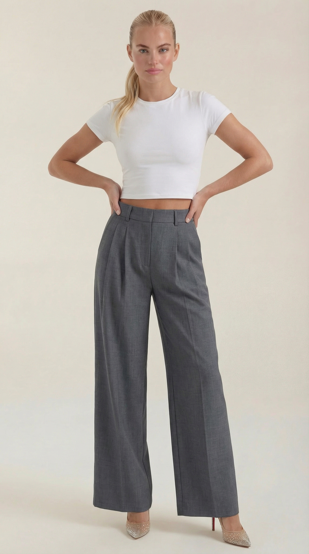 Female model in elegant wide-leg trousers front studio plain background.