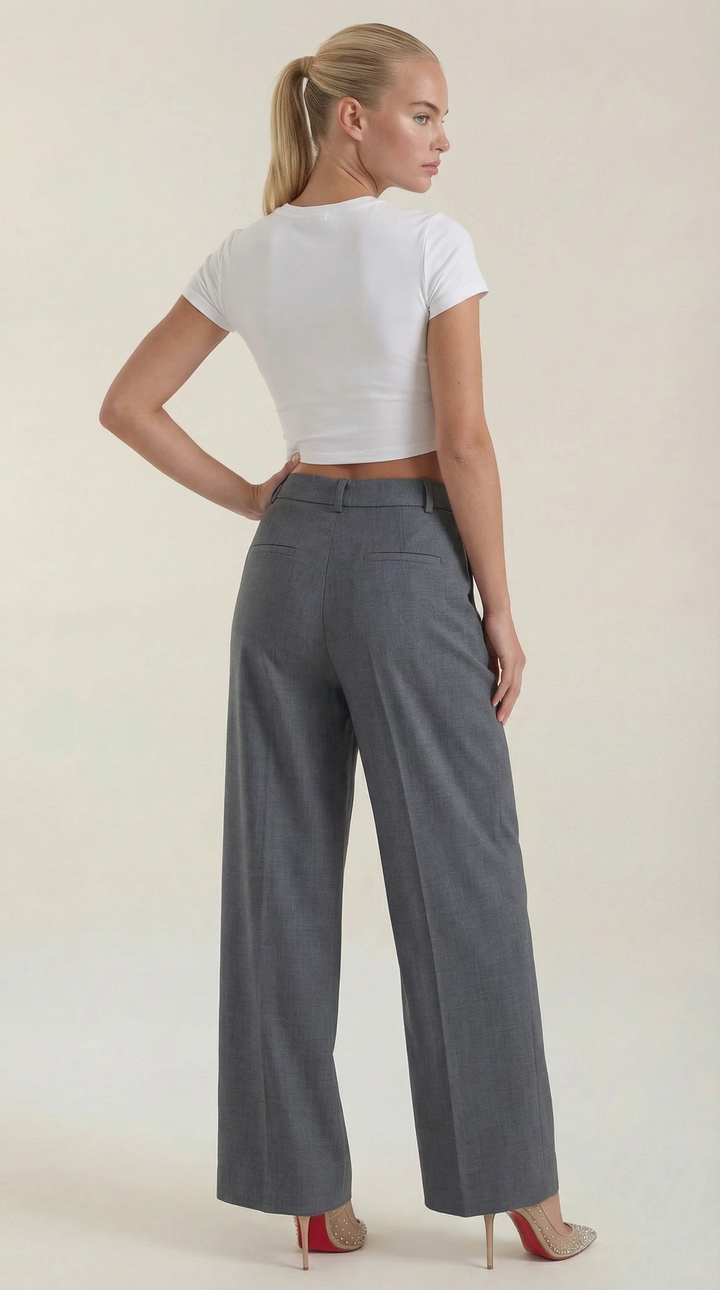Woman in chic high-waist pants back studio plain background, back view