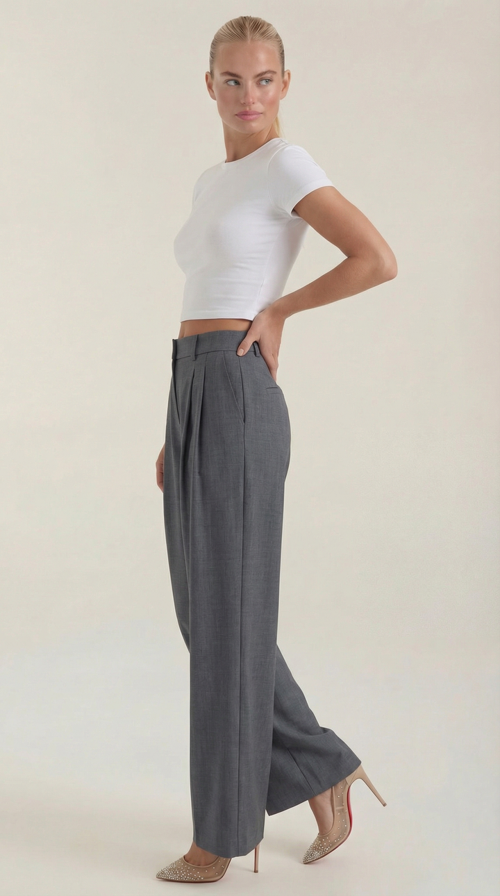 Woman showing side profile of tailored pants plain background.