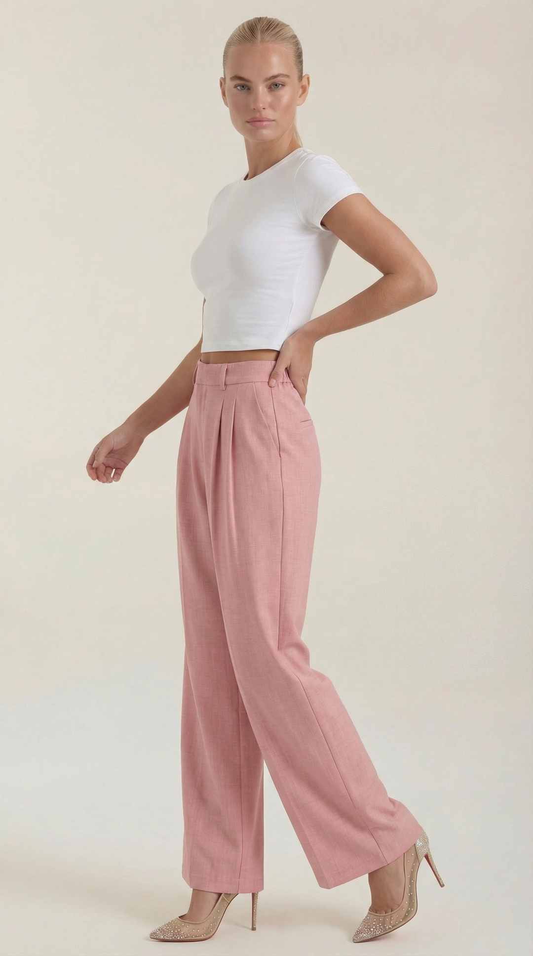 Female model displaying relaxed wide-leg pants side angle plain background.