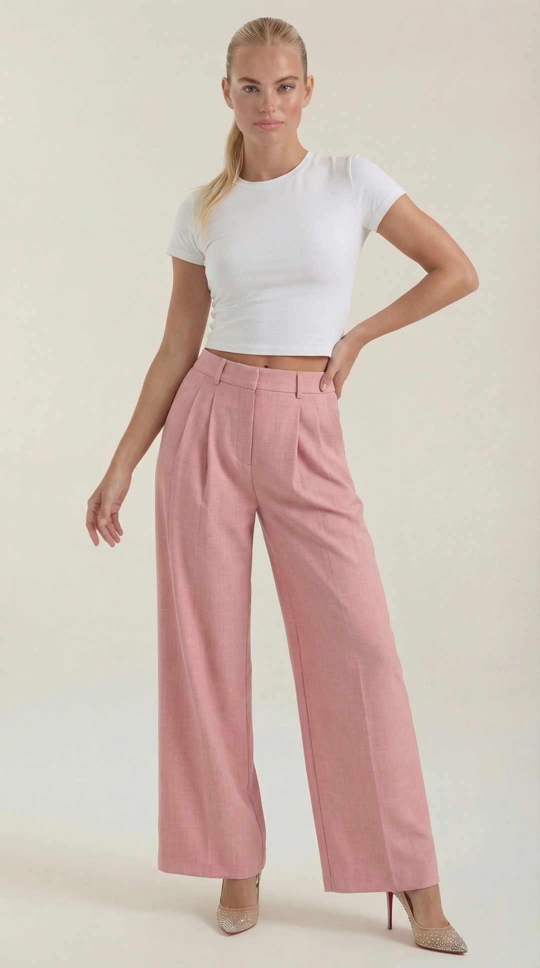 Woman wearing flowy pleated trousers front view plain background.