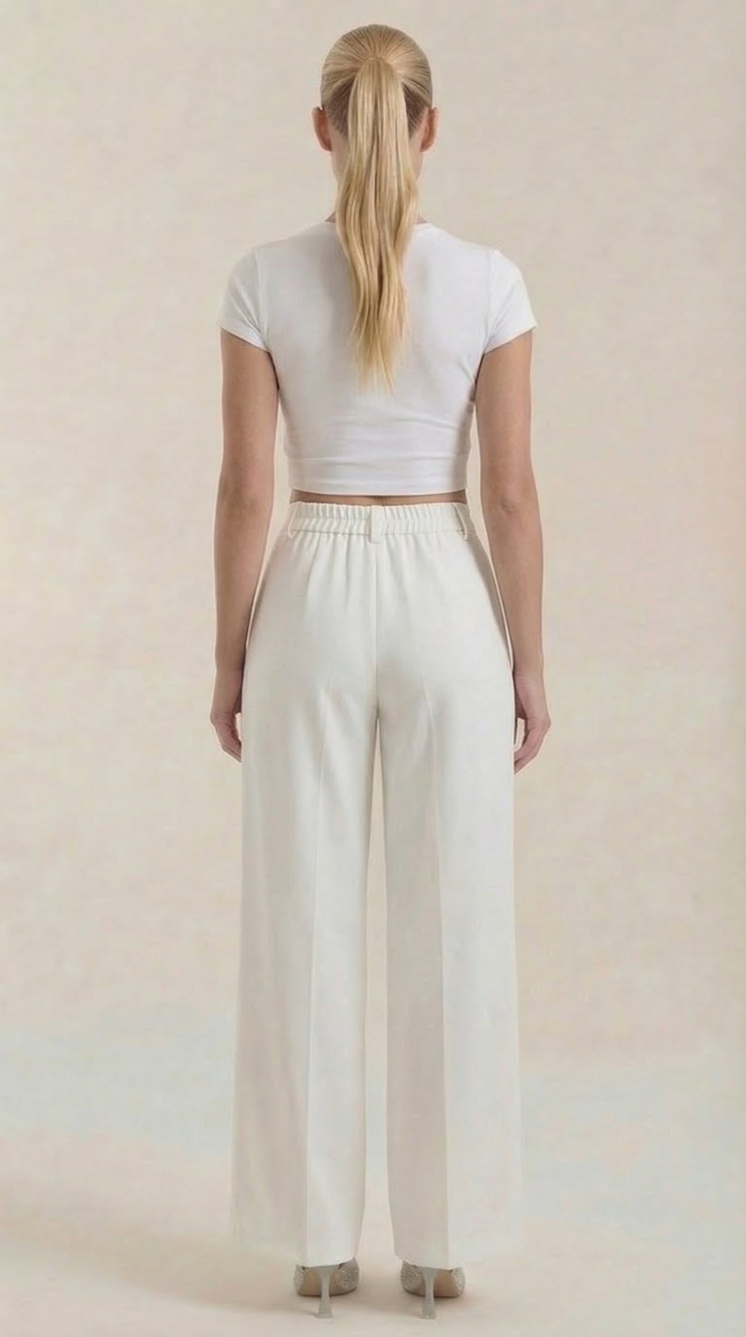 Female model showing relaxed fit pants on a plain background, back view