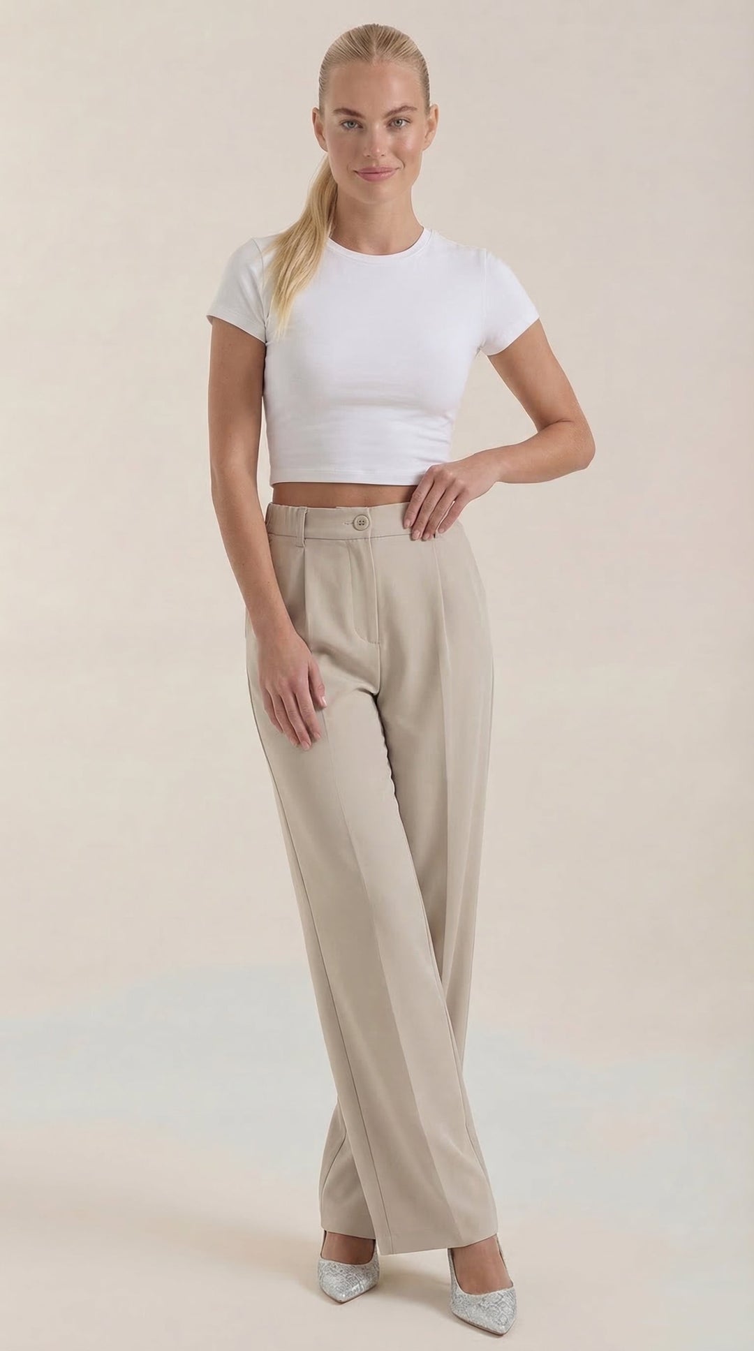Woman in elegant wide-leg trousers, side view, plain background.