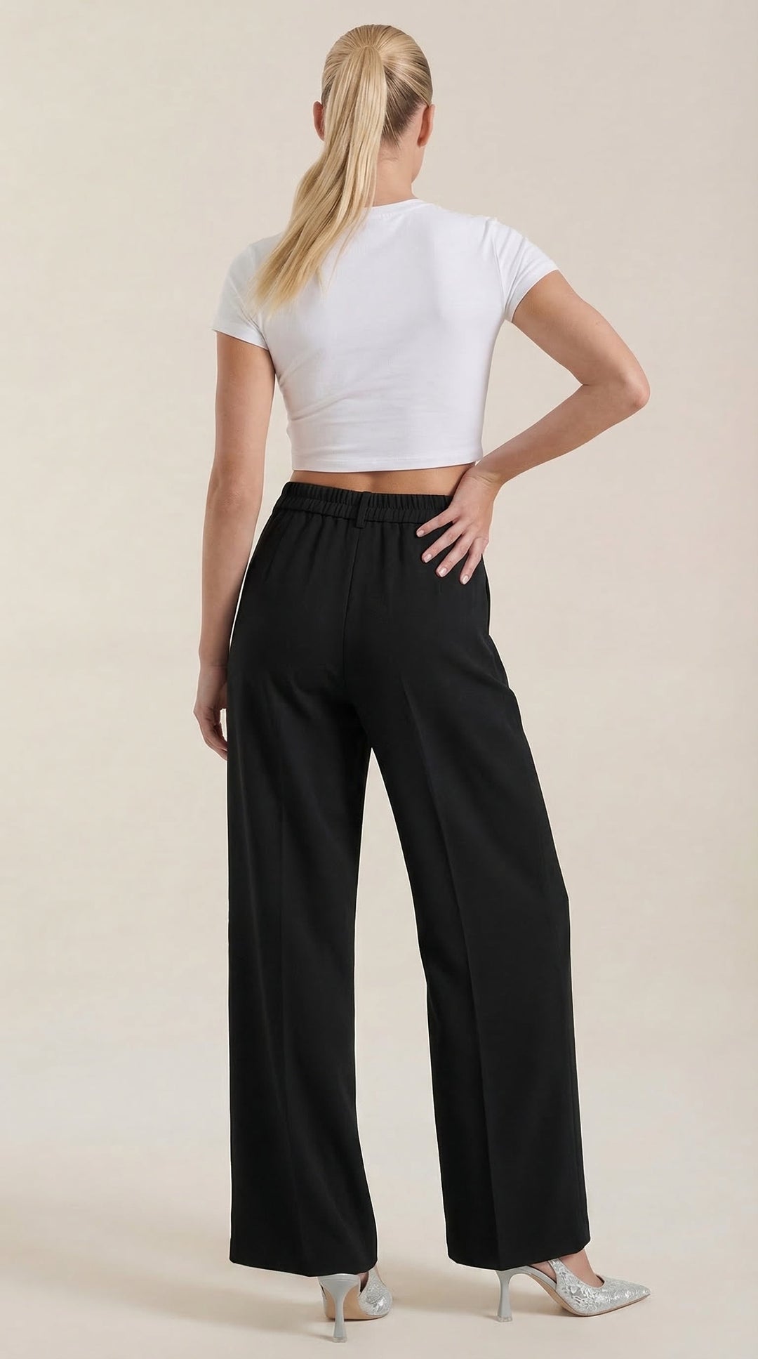 Woman wearing wide-leg trousers on a plain background, front view.
