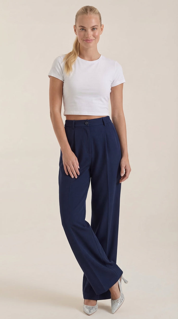 Female model showing back angle of trousers, plain background.