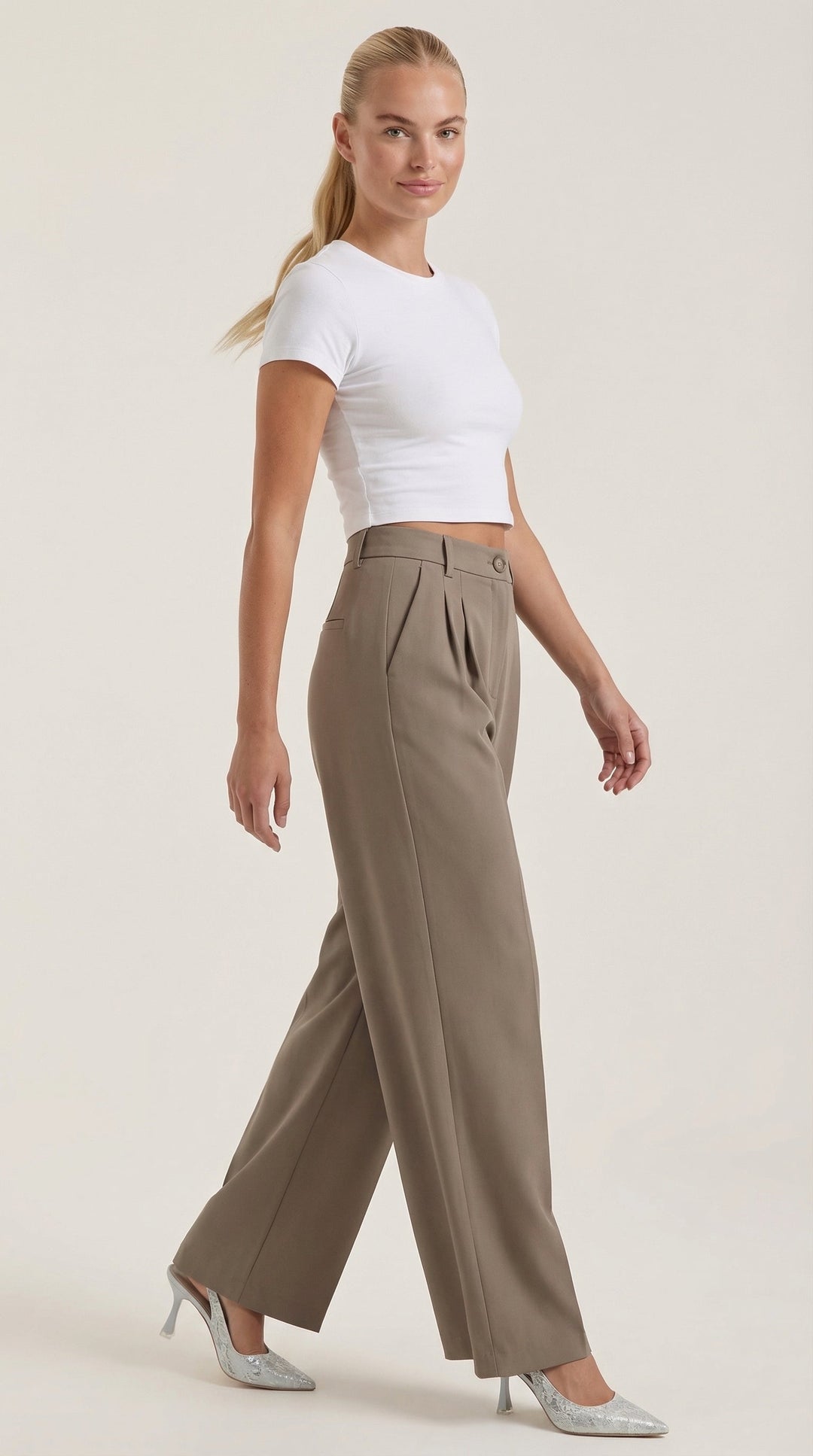 Woman displaying loose-fit office pants on a plain background, side views