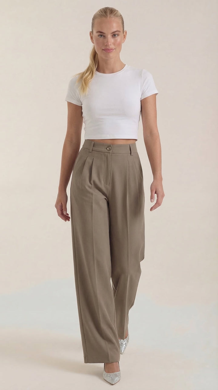 Woman posing in smart casual trousers on a plain background.