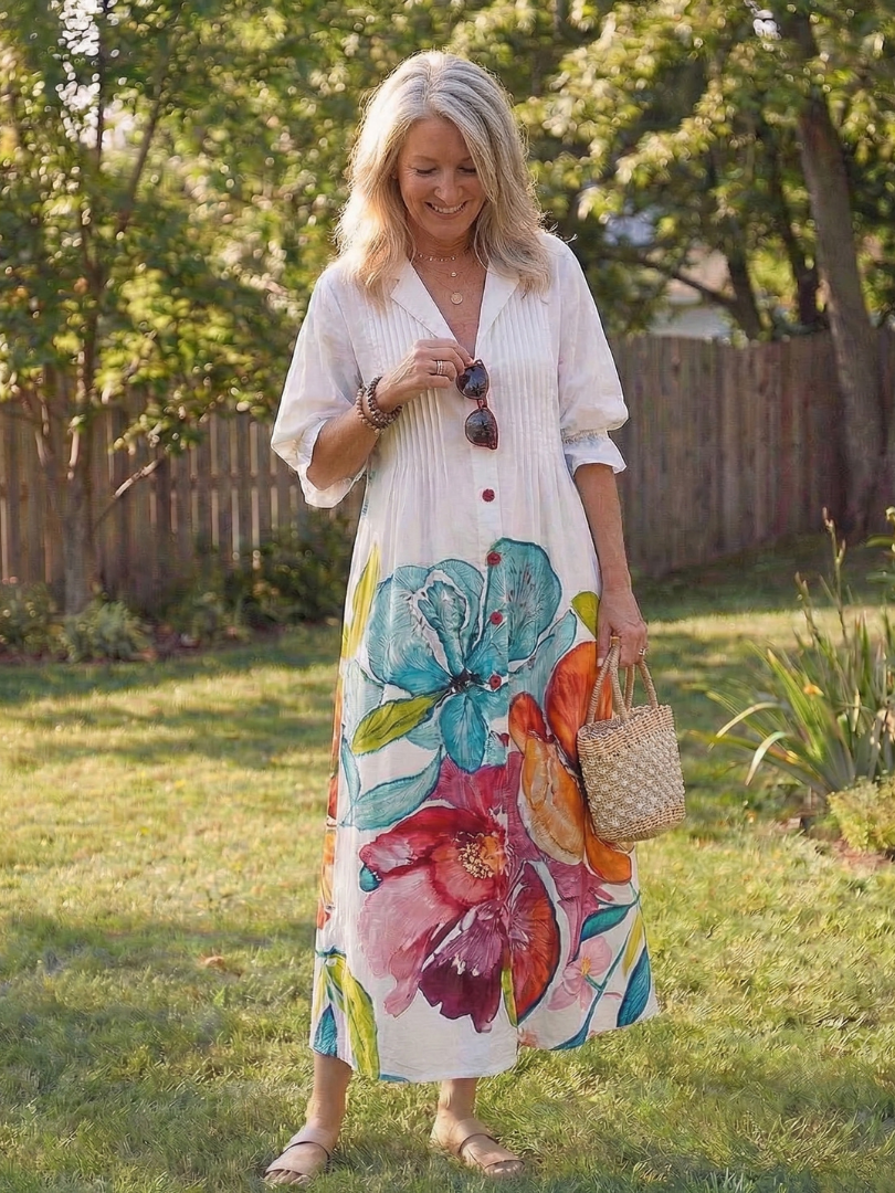 Female model styled in a long floral dress with elegant drape against a clean background.