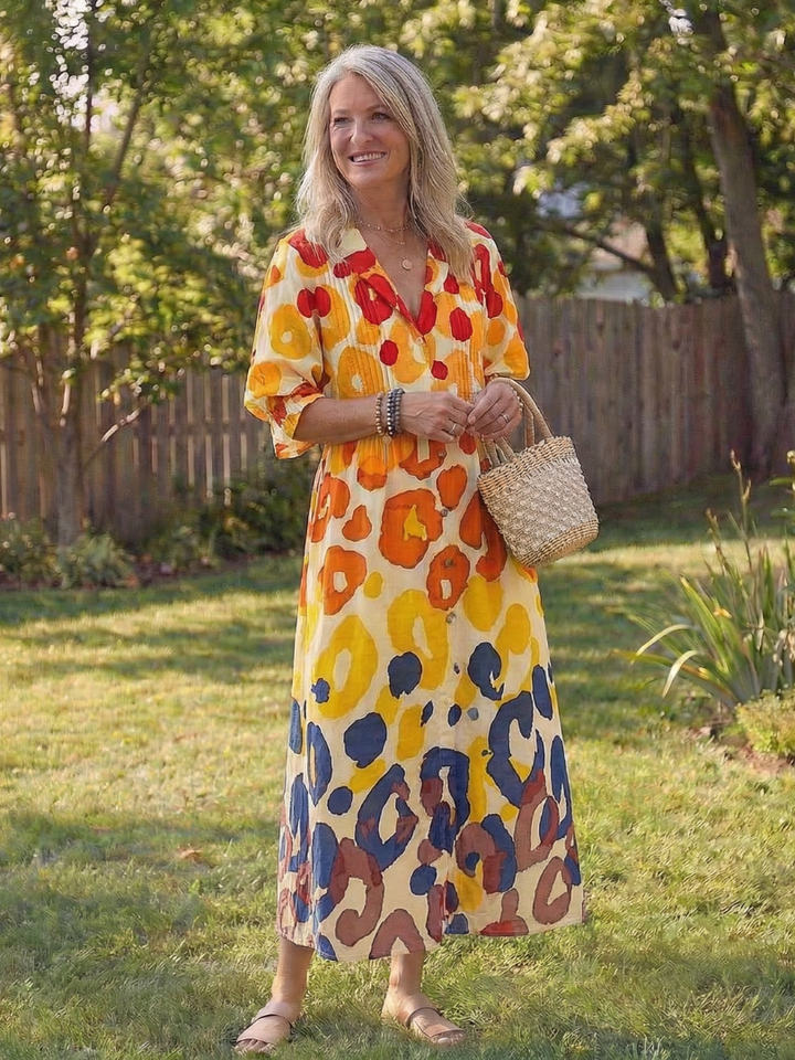 Woman wearing a vibrant floral maxi dress with 3/4 sleeves on a nature background.