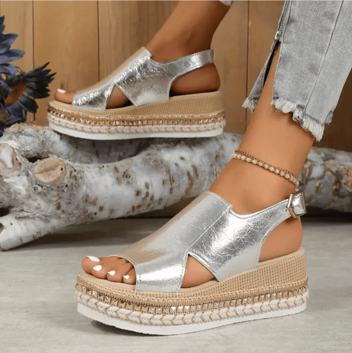 Pair of women’s heeled sandals shown on plain nature stone background.