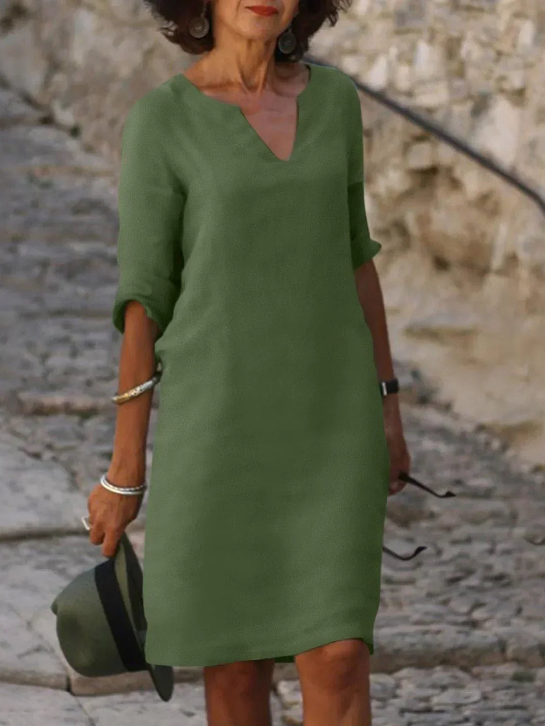 Front angle olive dress against rustic stone background