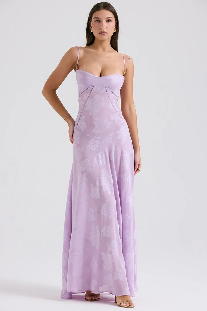 Woman posing in a breezy long dress with flowing silhouette on a plain background.