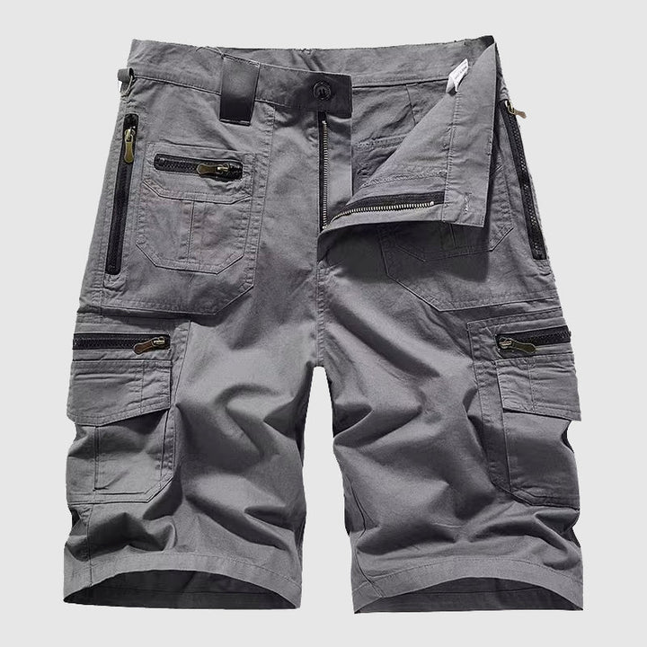  Female model wearing rugged utility pants with flap and zip pockets on a plain background.