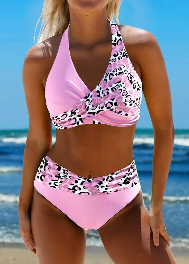 Woman in a stylish criss-cross bikini standing against a beach background.