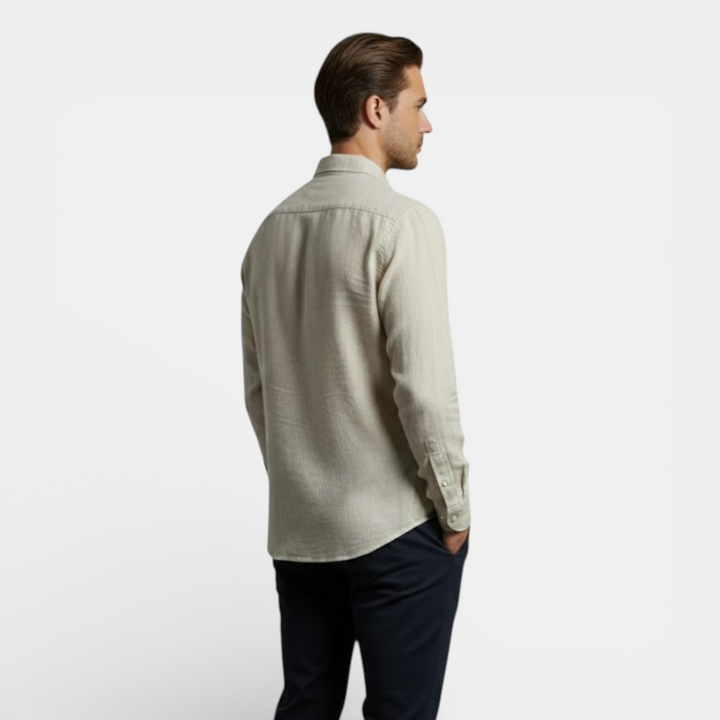 Female model in an airy button shirt with long sleeves against a plain background.
