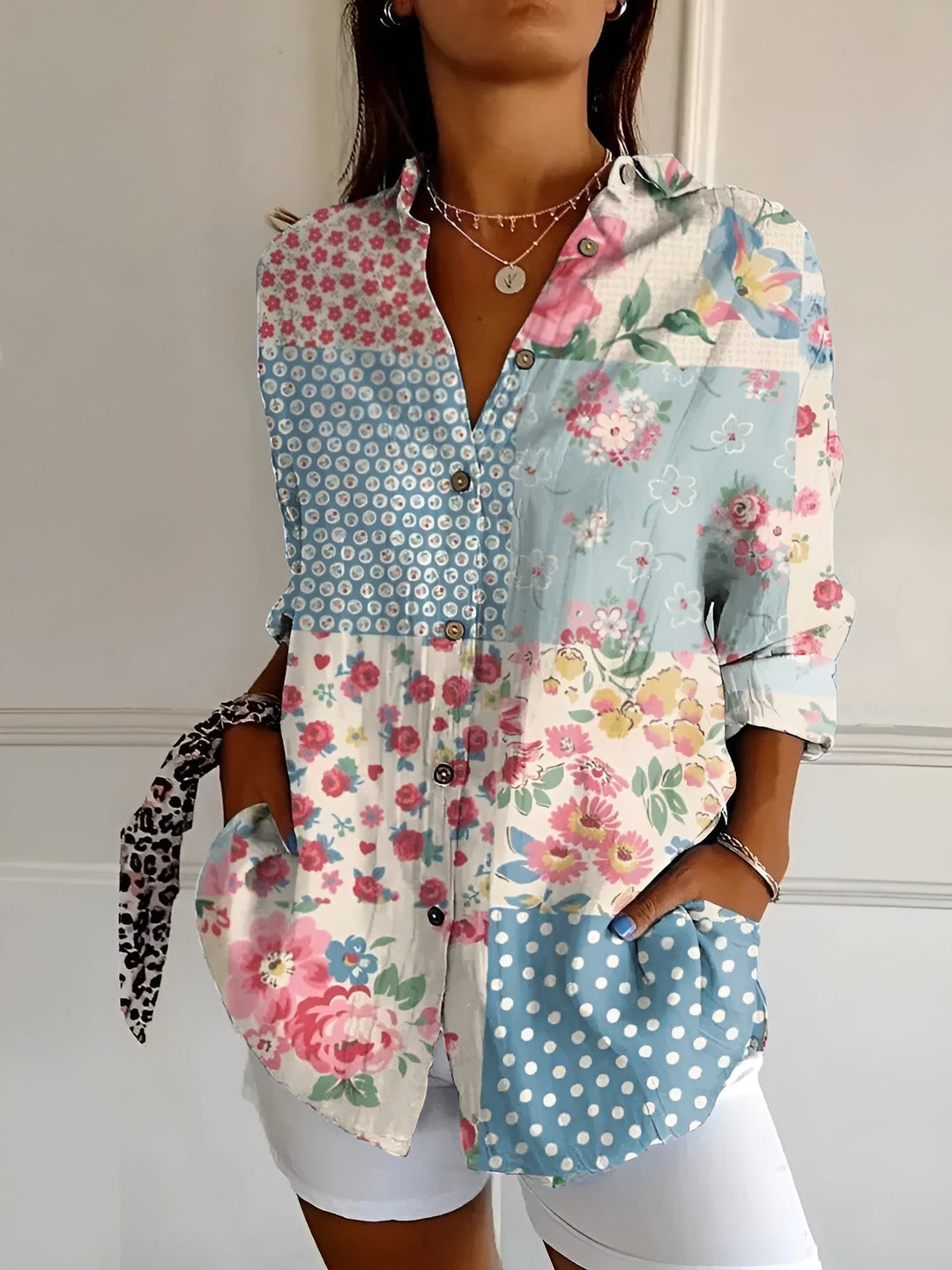 Female model in a relaxed summer floral blouse with a plain background.