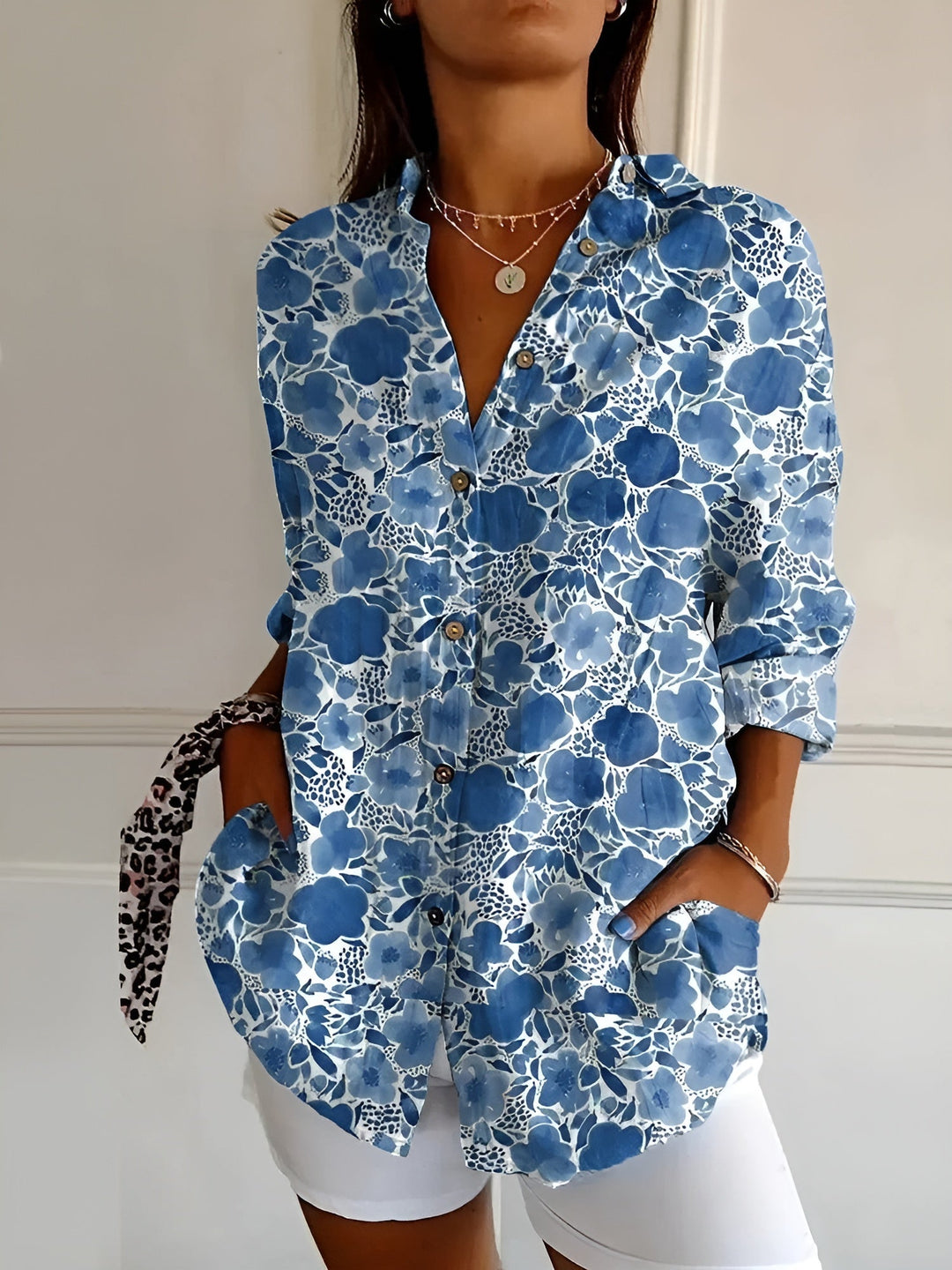 Female model wearing a floral button-front blouse against a plain background.