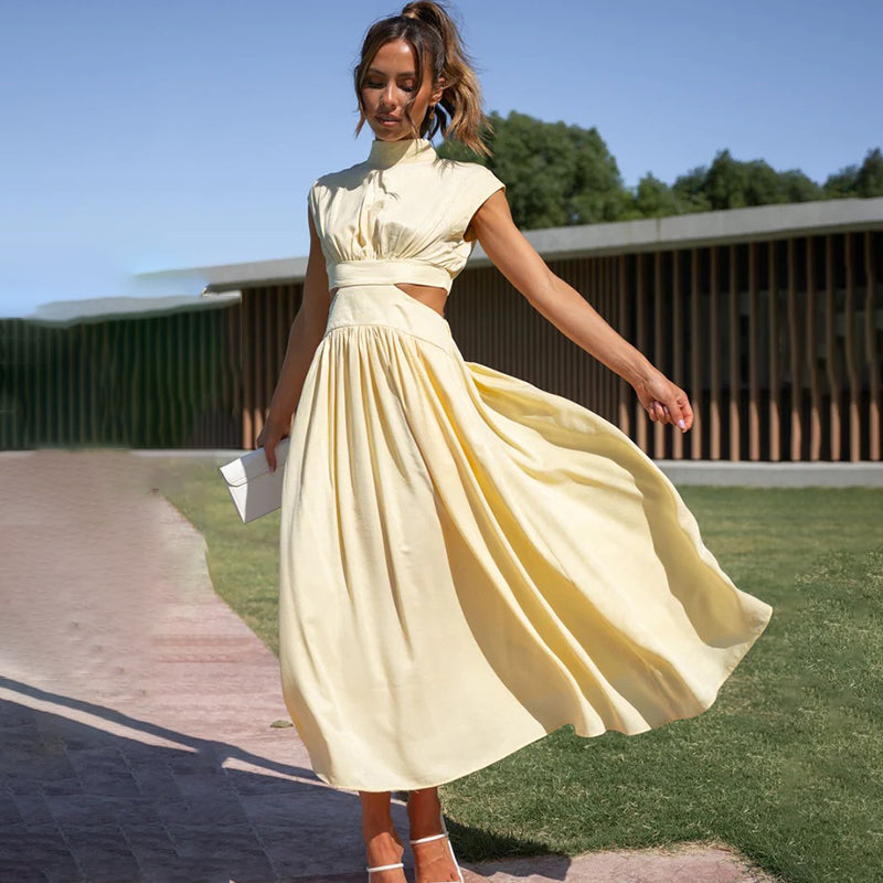 Woman in a loose floral maxi dress styled with a feminine silhouette against a plain backdrop.