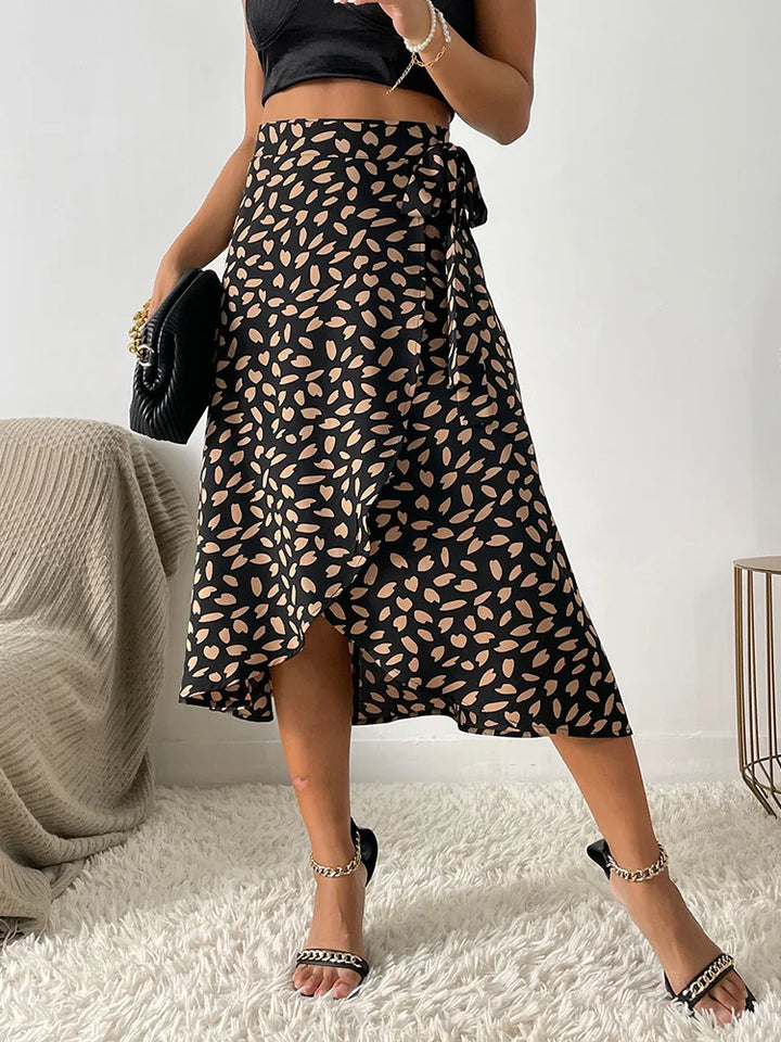  Female showcasing a patterned wrap skirt with a flowing silhouette on a plain background.