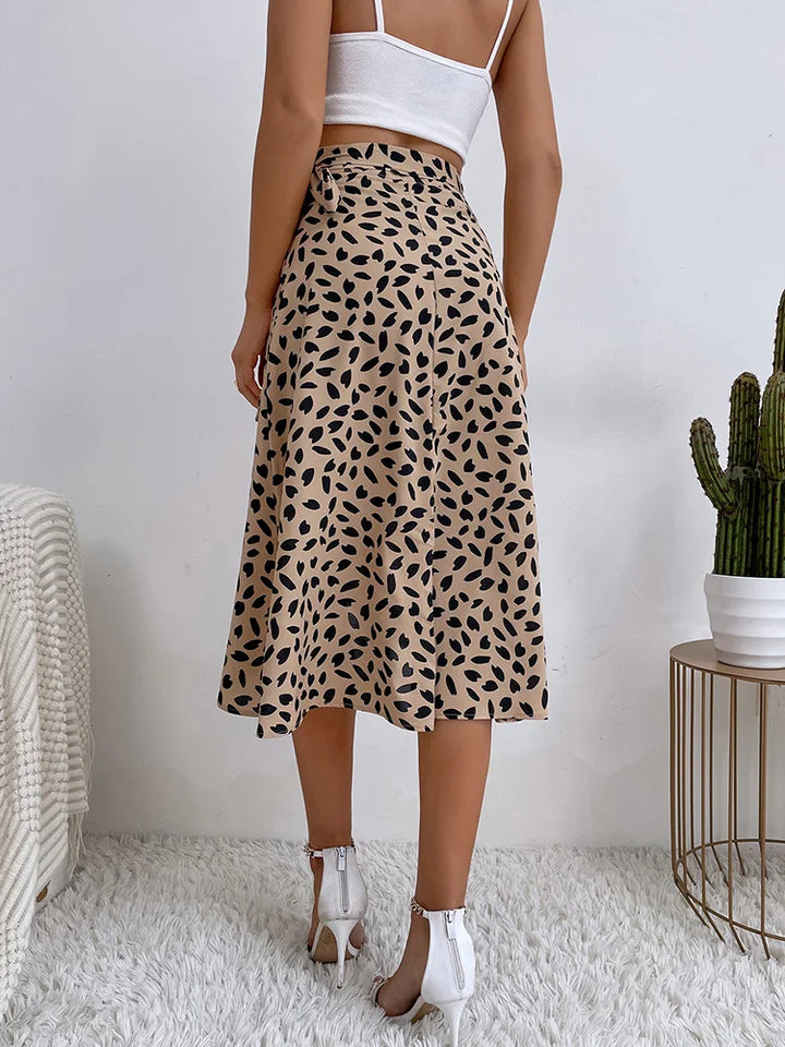  Female wearing a flowing patterned skirt styled for warm-weather outfits on a plain background.