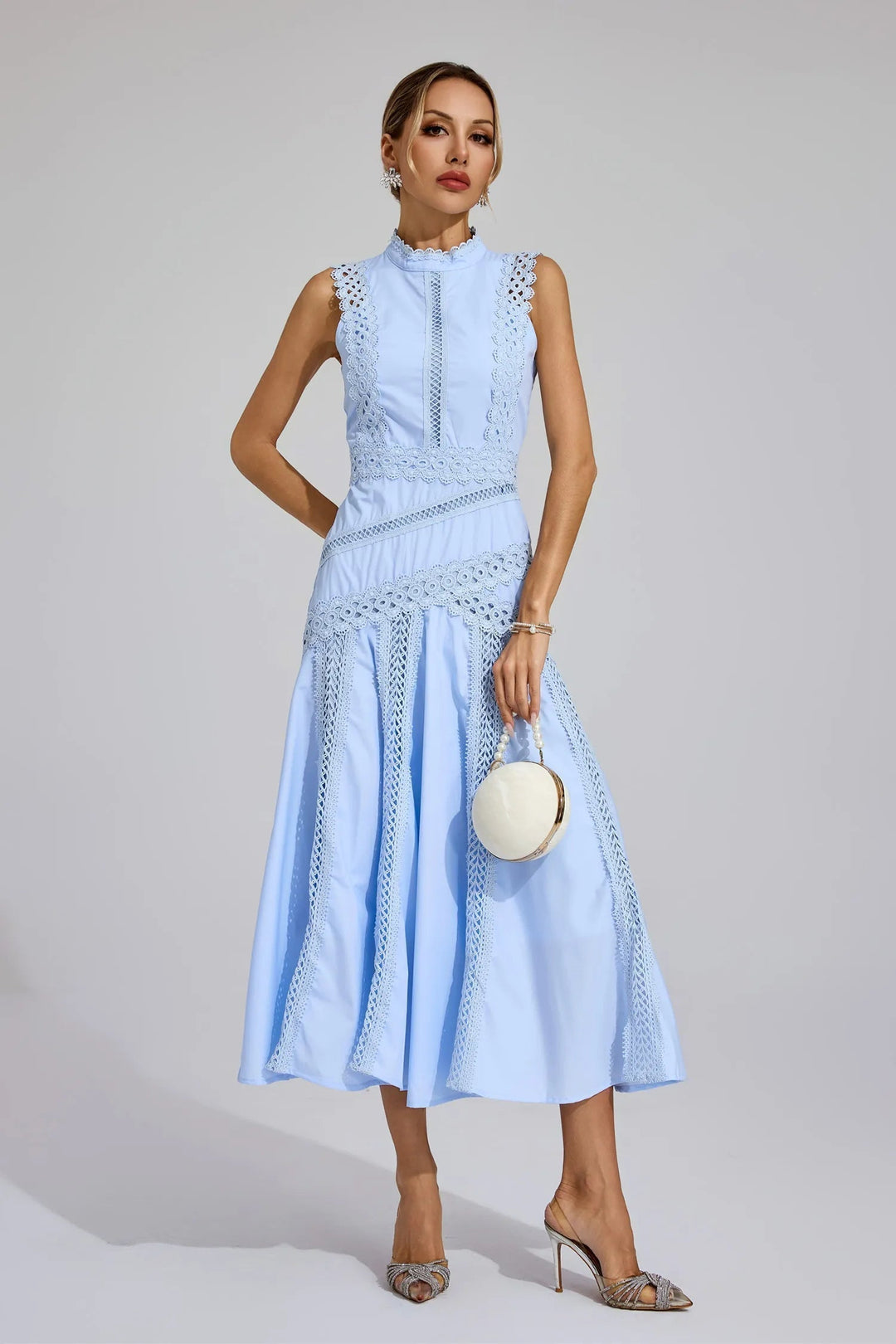 Female model in a midi dress featuring decorative details and a softly flared skirt.
