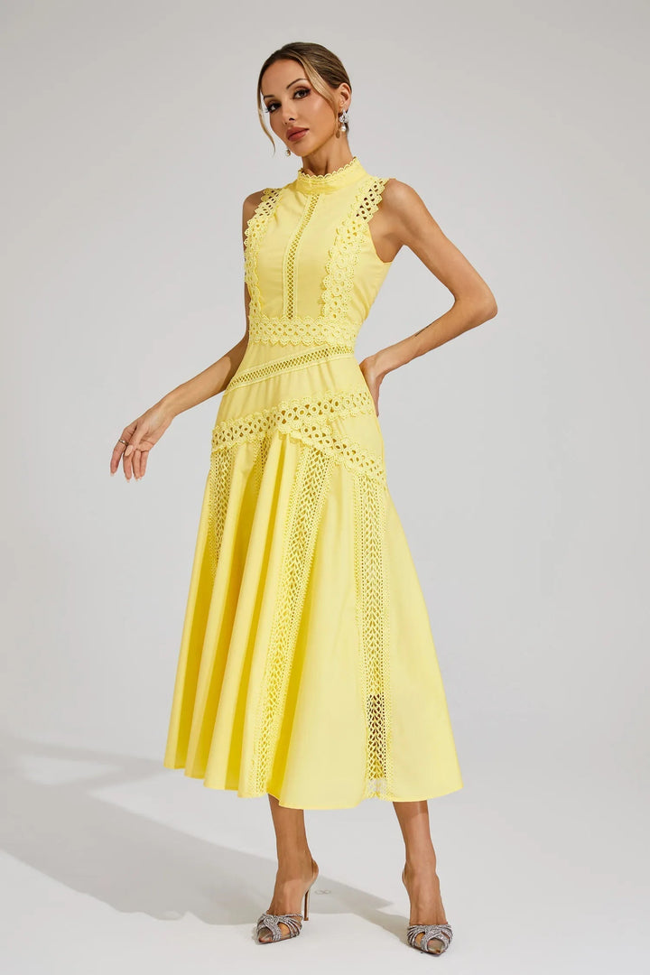 Woman in an elegant sleeveless midi dress with a flowing skirt on a plain background.
