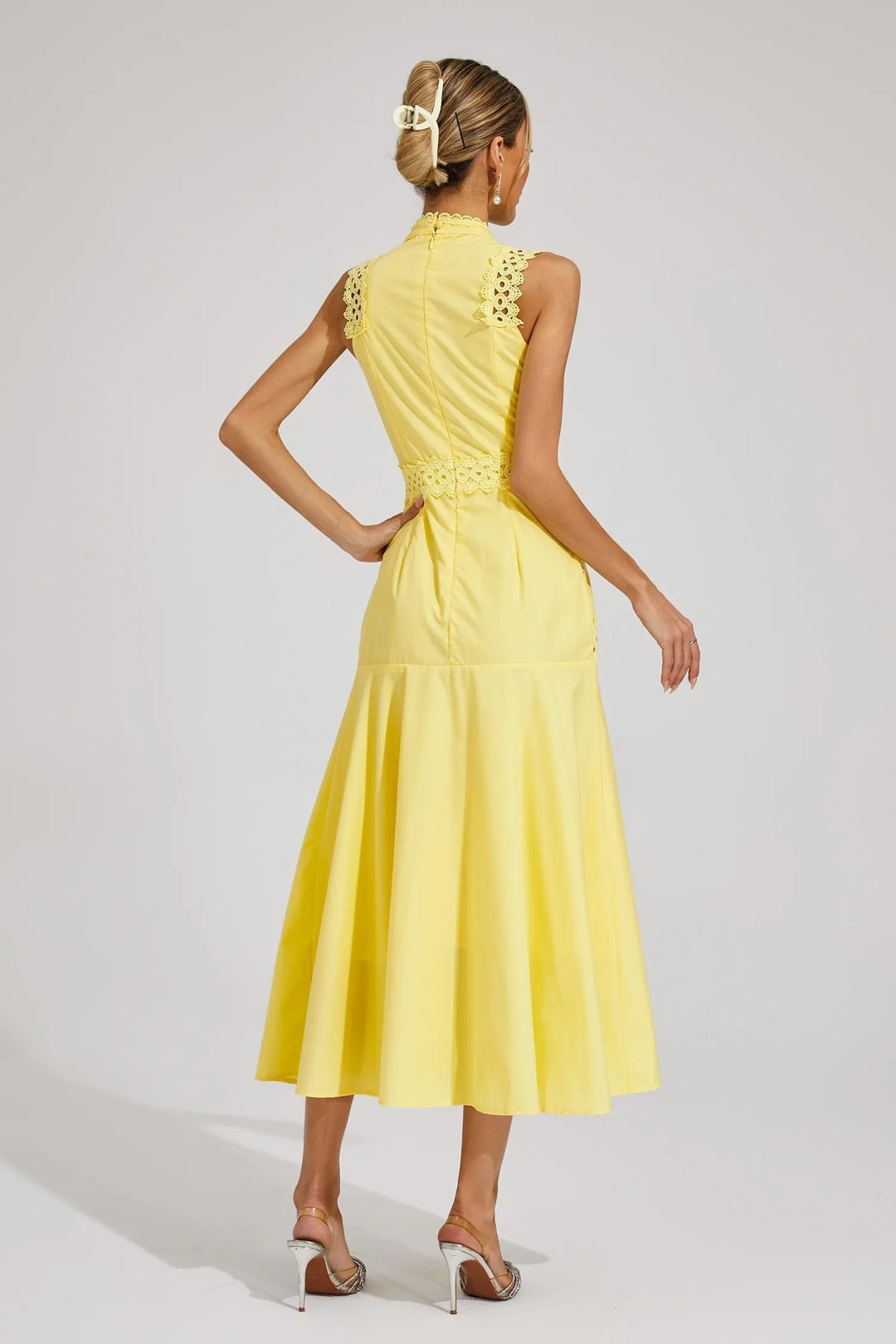 Woman wearing a sleeveless occasion dress with a refined silhouette against a plain background.
