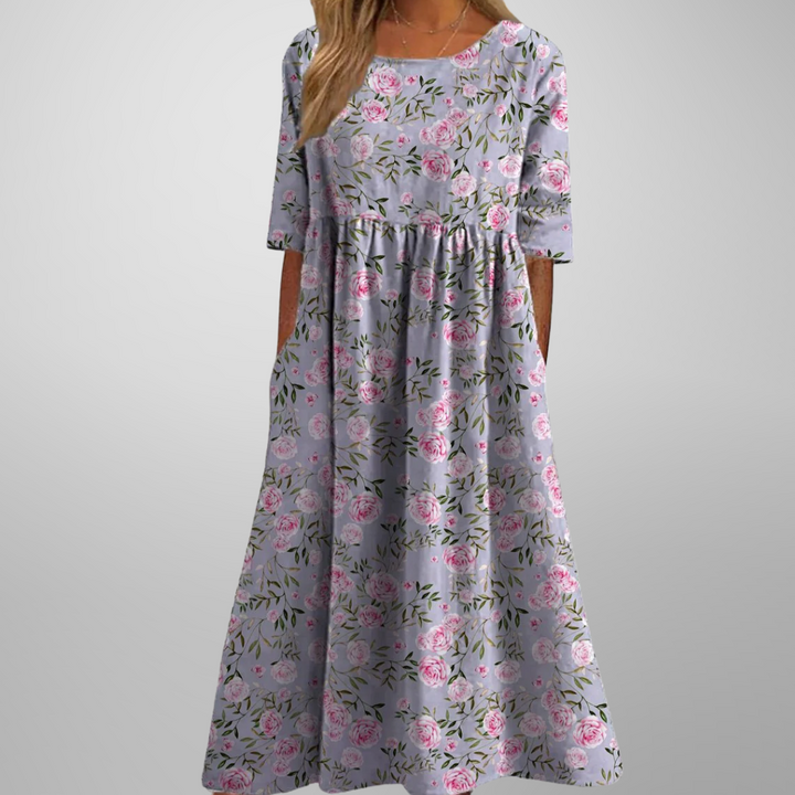 Woman model showcasing a women’s floral maxi dress with pockets on a plain background.