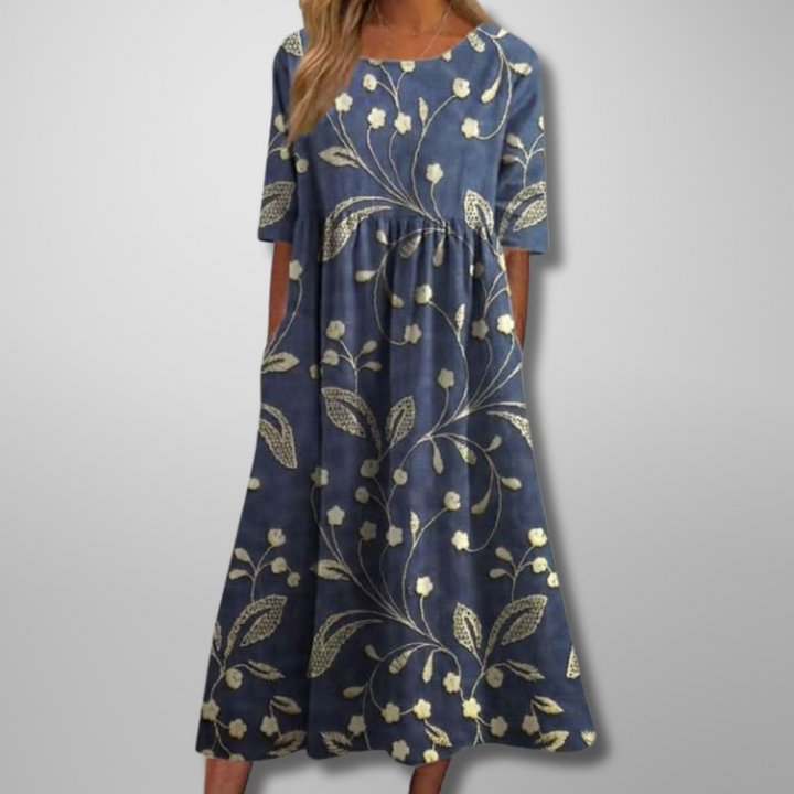 Woman model wearing a floral maxi dress with pockets on a plain background.