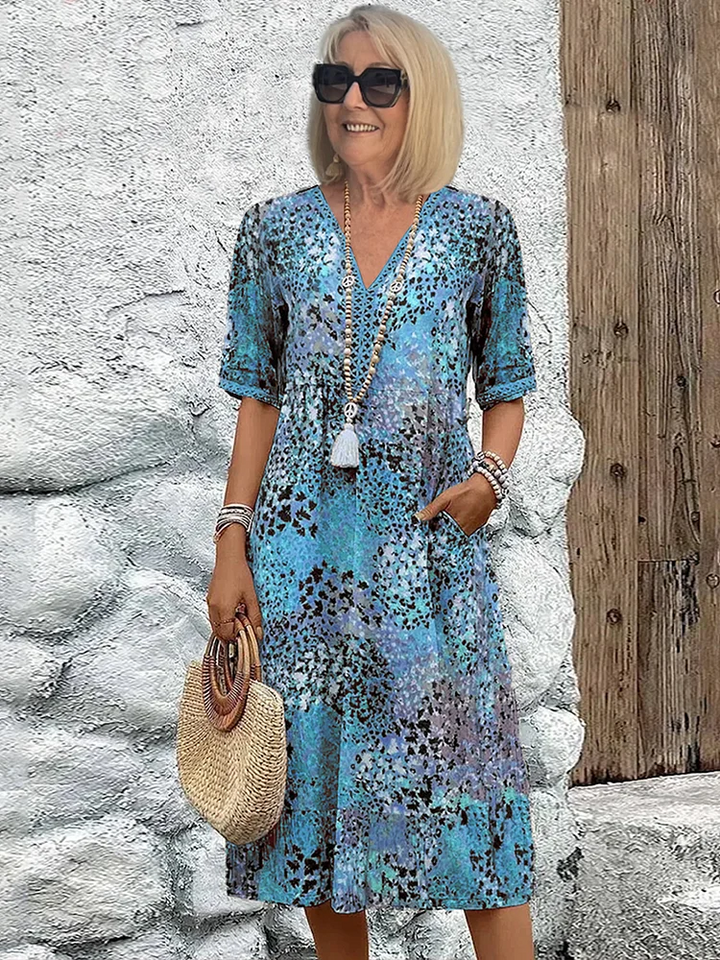 Model showcasing a casual printed midi dress with pockets on a plain background.