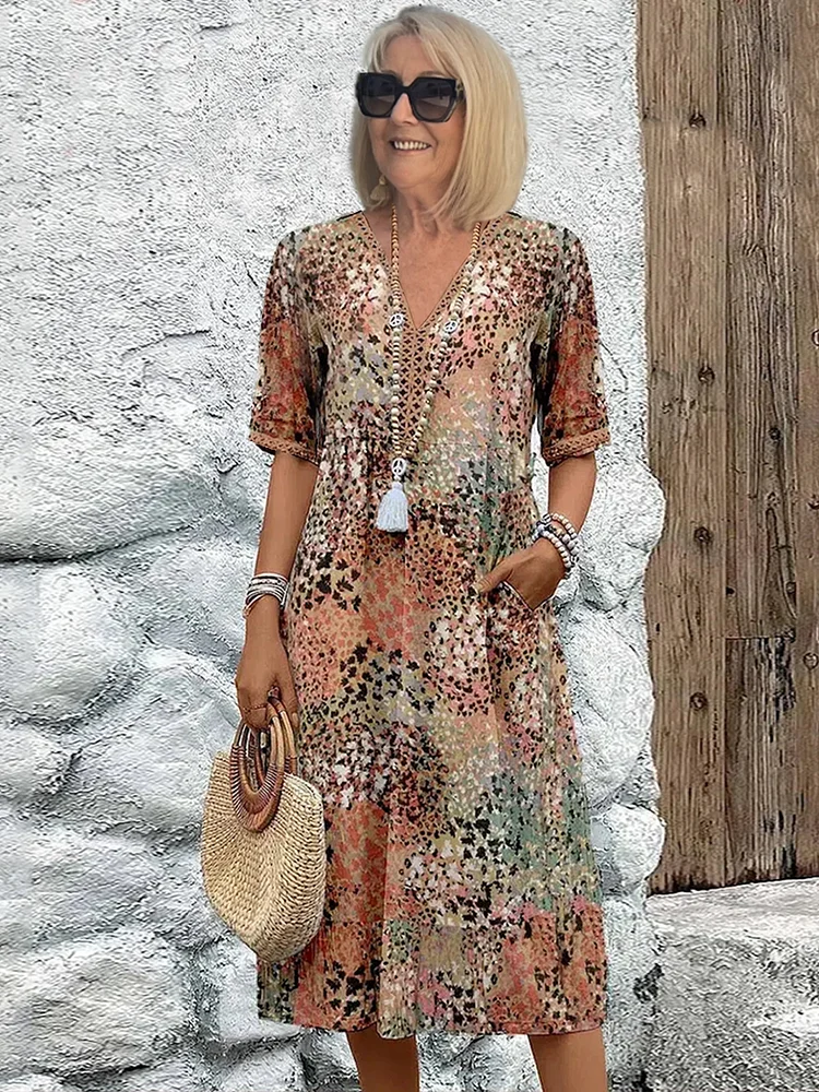 Woman model posing in a vibrant printed midi dress with functional pockets on a clean background.