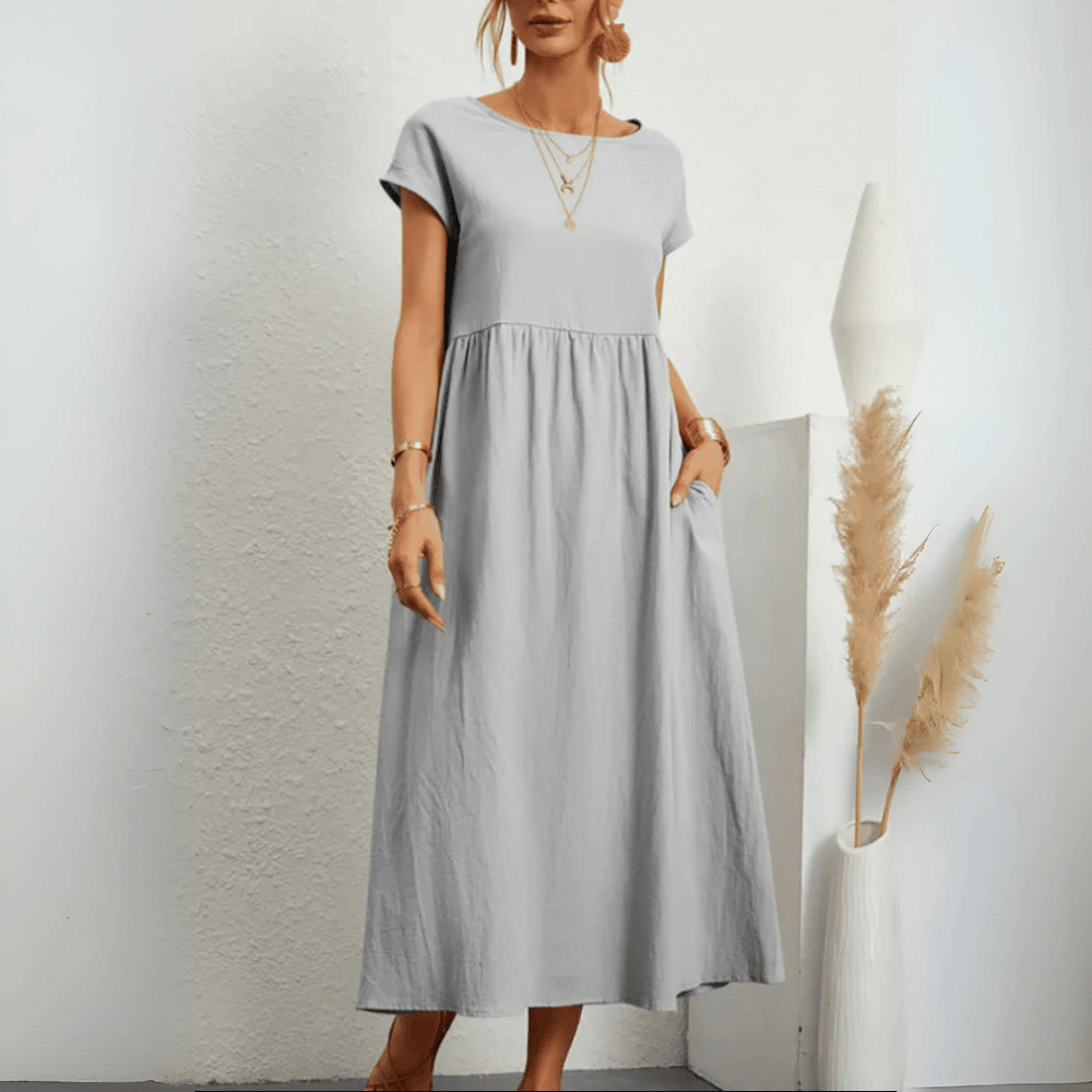 Model in a short sleeve empire waist midi dress on a plain background.