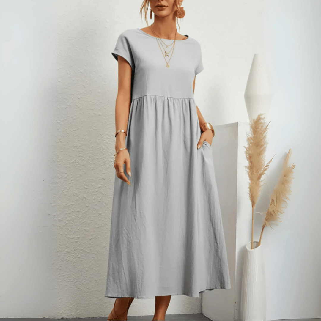 Model in a short sleeve empire waist midi dress on a plain background.