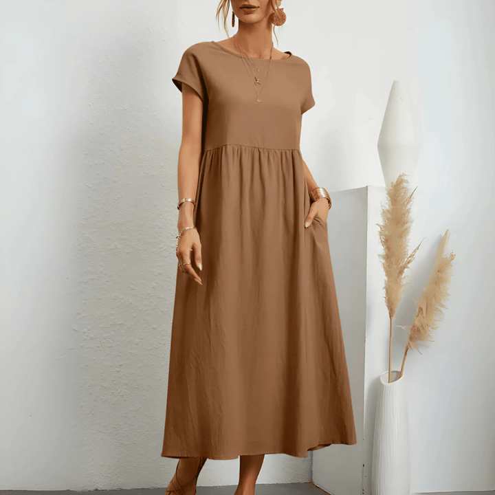 Woman model wearing an A-line midi dress with pockets on a clean background.