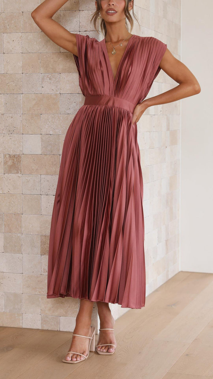 Woman model in a V-neck pleated midi dress against a plain background.
