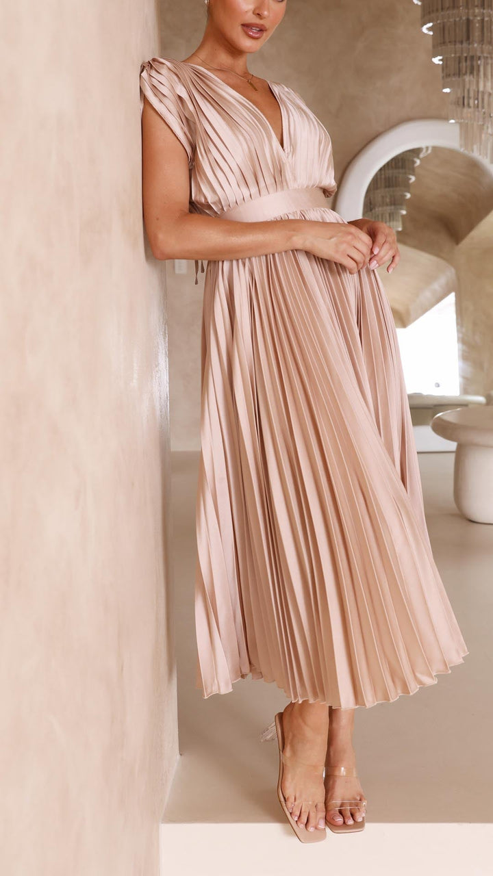 Woman model in an A-line pleated midi dress with a simple clean backdrop.