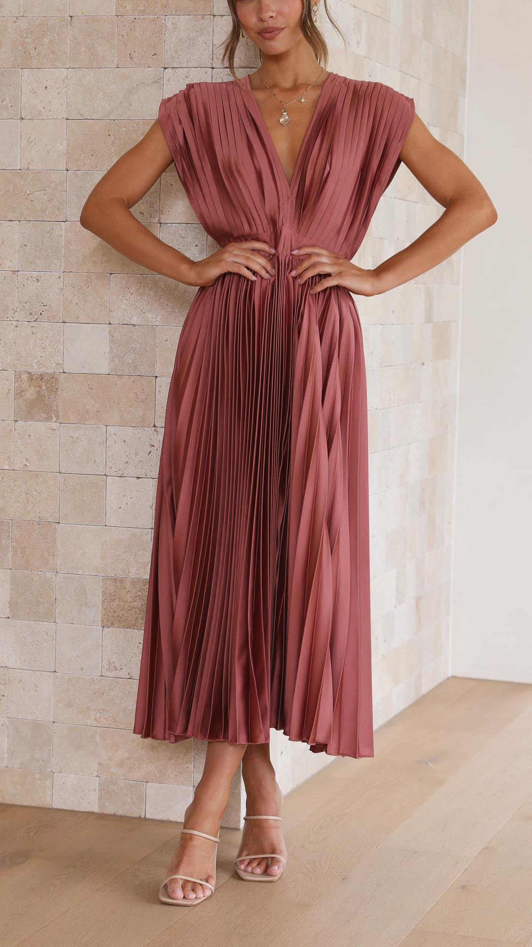 Woman model wearing a sleeveless pleated midi dress on a clean background.