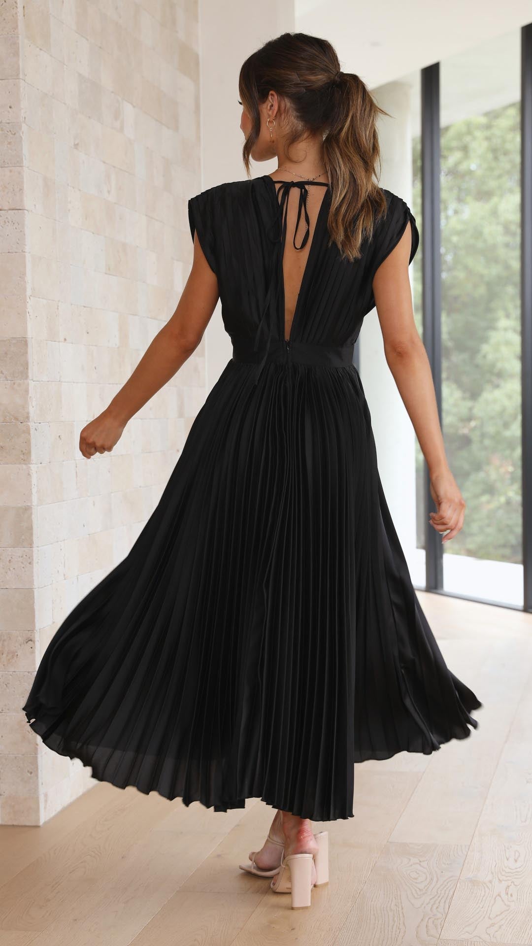 Sleeveless pleated A-line dress photographed on a woman model, back view