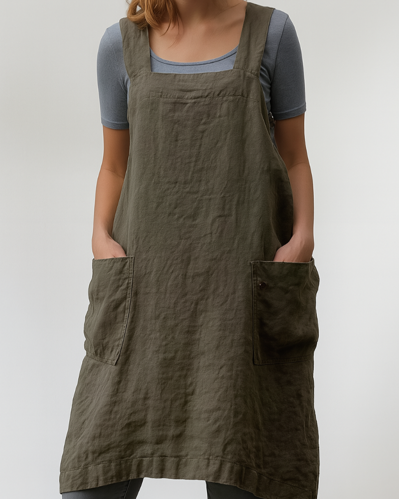 Model wearing a casual sleeveless apron dress on a plain backdrop.