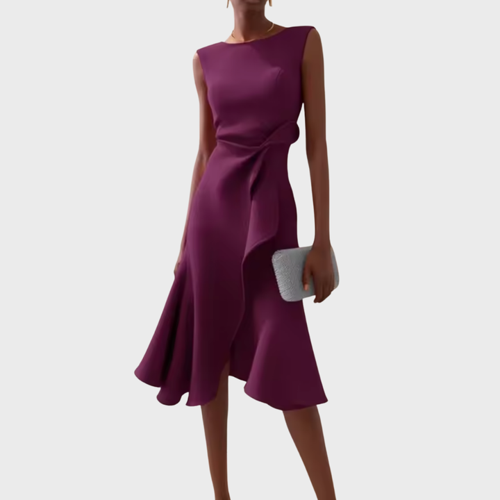 Woman model in a sleeveless asymmetrical hem dress on a plain backdrop.