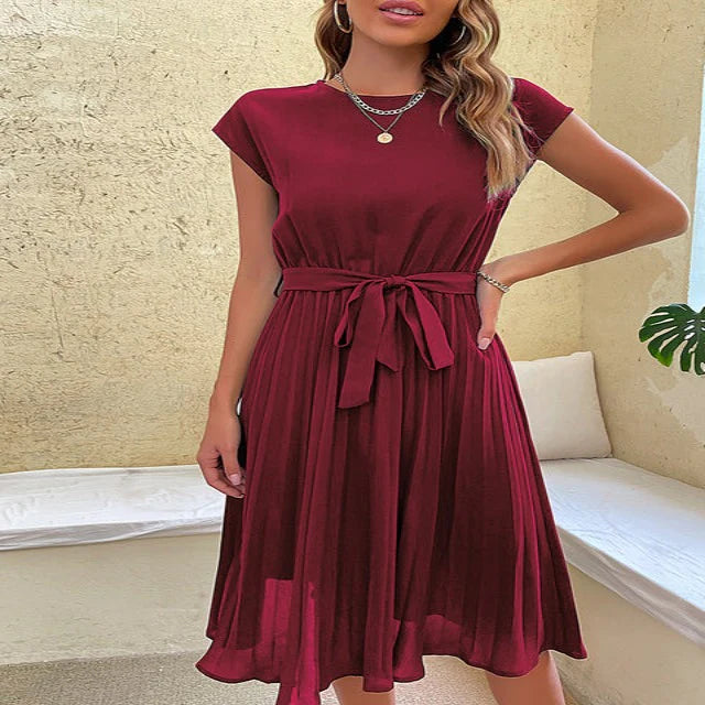 Woman posing in a versatile pleated midi dress with a flattering A-line silhouette.